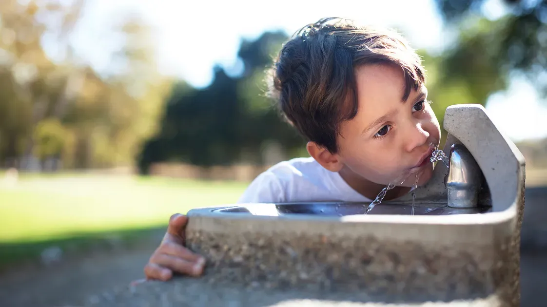 Child drinking from a public water fountain