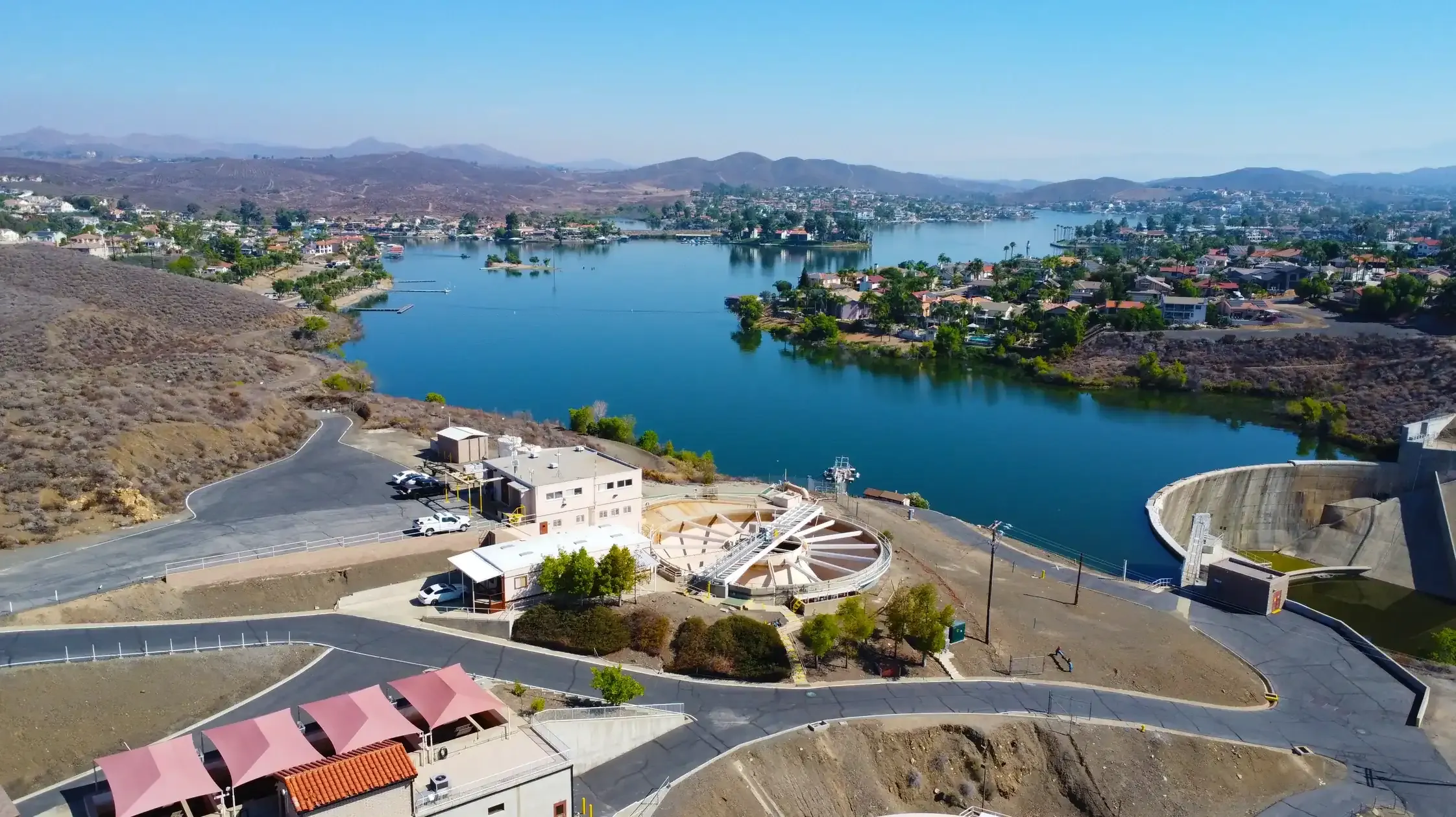 Aerial view of a California reservoir and dam ringed by hillside homes